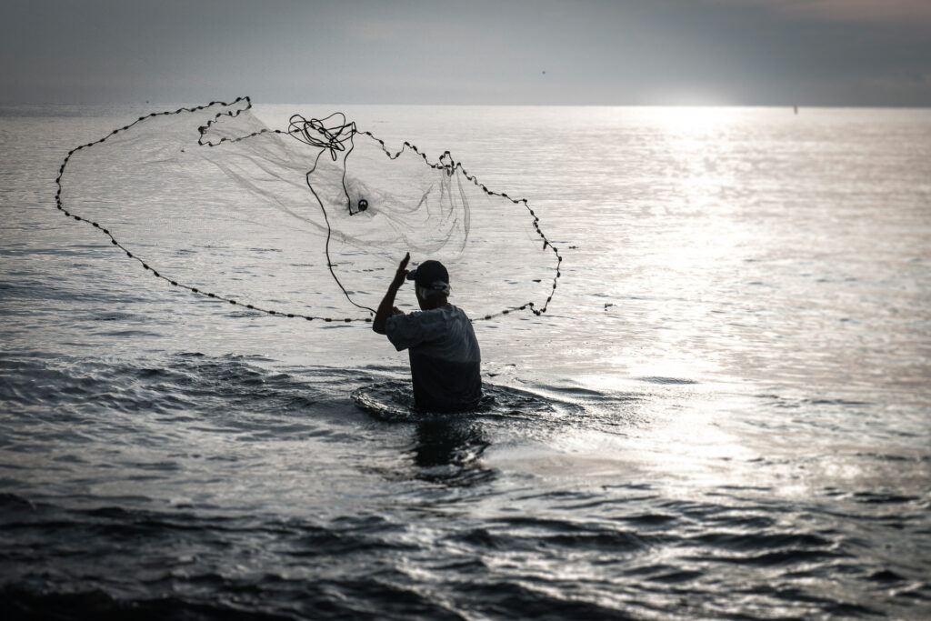 Your Beginner's Guide to Fishing in Florida - Fisherman cast a net to catch bait